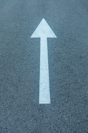 A white arrow going straight painted on the asphalt