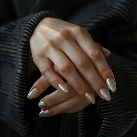 Female hands with long nails and gray manicure holding a bottle of nail polishの素材