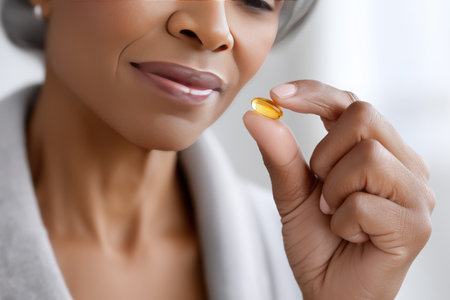 Closeup of young woman taking vitamin pill. She is looking at camera and smilingの素材