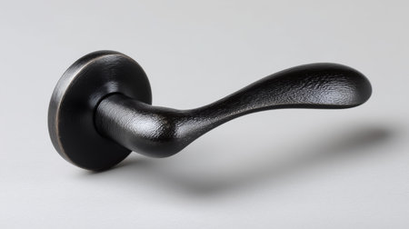 This black door handle features a modern, curved design with a textured finish. Set against a light grey background, it highlights details of quality material and craftsmanship.の素材