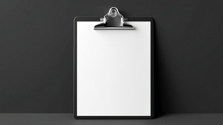 A clean, empty clipboard rests against a dark surface, ideal for jotting down ideas or creating designs. The metallic clip shines as it holds the untouched paper firmly in place.の素材