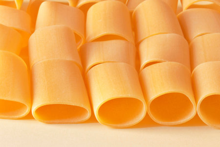 Lines of paccheri pasta on a light yellow background ,in evidence irregular pasta shapes ,horizontal composition の写真素材