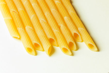 A layer of penne italian pasta lined on a white background ,top view ,pasta shape highlighted