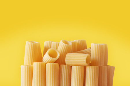 Italian pasta called rigatoni on a colored background ,tube-shaped pasta with ridges down their lenght , studio shot ,の写真素材