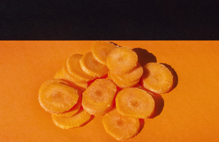 A beautiful bunch of sliced carrots on a colored background   ,top view ,studio shot , orange and black color harmonyの写真素材