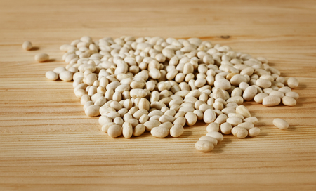 A beautiful heap of white beans on a wooden board, front view, studio shotの写真素材