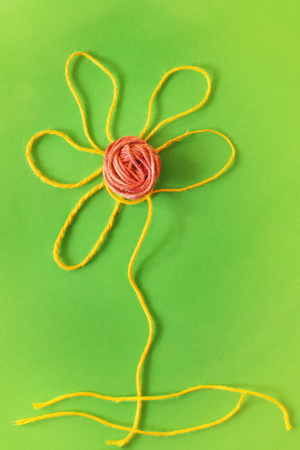 Flower made with thread, symplicity and stylization to create a long stem and a flower head.の写真素材