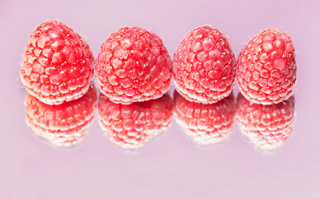 Four bright raspberries on a mirror form their double .の写真素材