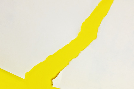 A white ripped paper rests on a yellow background ,beautiful paper edge , top viewの写真素材