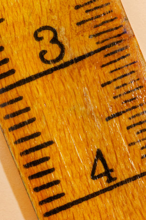 Numbers three and four on a yellow  wooden ruler , black lines along the edges ,the ruler is worn...