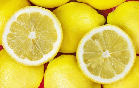 Two lemons half cut  on lemon fruits and red  background , studio shot の写真素材