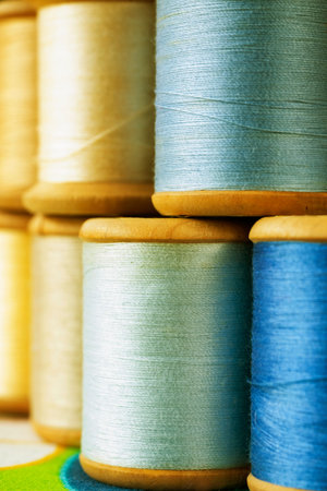 Different wooden spools of colored thread on  colored background , different shades of blue and...