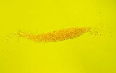 Yellow grains of cornmeal  on colored background ,itâ€™s a common staple food  of Northen...