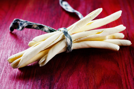 Italian pasta called maccheroni calabresi on red wooden background ,long and thick pasta made with...