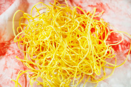 Uncooked pasta fettuccine on colored background , yellow flat thick pasta made with egg and flourの写真素材