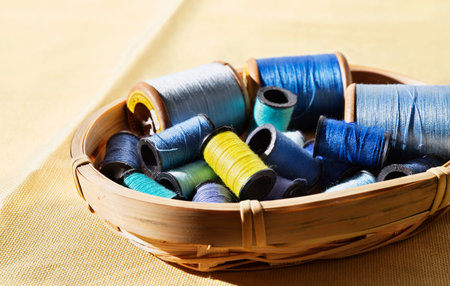 Spools of blue thread and one yellow spool in basket, different size spools