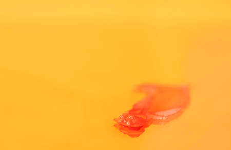 Orange spot of paint on mirror, beautiful reflection on orange backgroundの写真素材
