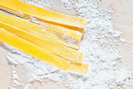 Large flat egg pasta pappardelle with flour on wooden background, uncooked pastaの写真素材