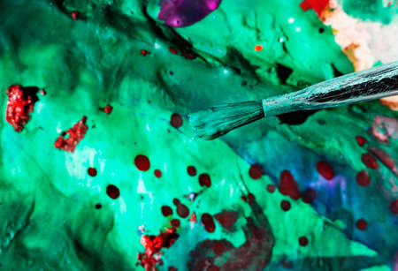 Used paint brush with green paint, in the background green and red color spotsの写真素材