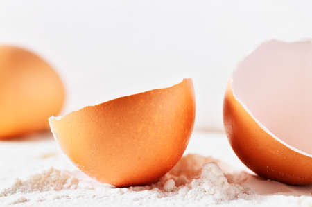 Broken eggshell with flour on white backgroundの写真素材