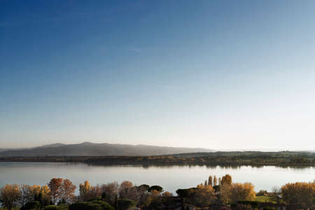 View of Lake Trasimeno from Castiglione del Lago in autumn, in the background small villagesの写真素材
