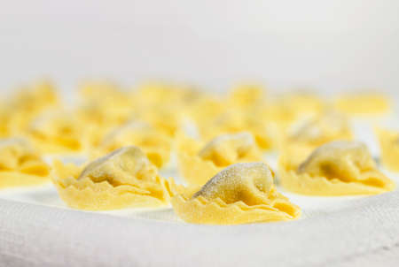 Italian tortellini on white cloth, uncooked stuffed pastaの写真素材