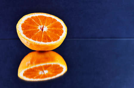 Half orange fruit on mirror on blue background, mirror reflection,の写真素材