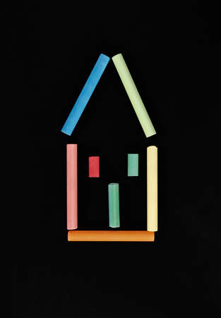 Colorful house shape with multicolored pieces of chalk on black backgroundの写真素材