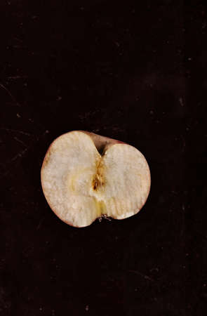 Red Annurca apple in half on dark ruined background, fruit cultivated in Southern Italyの写真素材