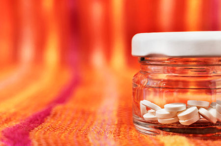 White pills in closed glass jar on colored background, hearth care and medicine