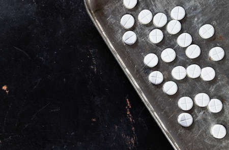 White pills on gray tray on dark background, hearth care and medicineの写真素材
