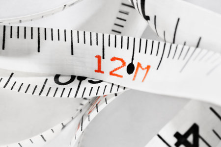 Detail of white measuring tape with number 12 on white background, carpentry tool,