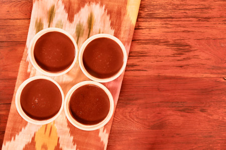 Four bowls with chocolate pudding on red wooden tableの写真素材