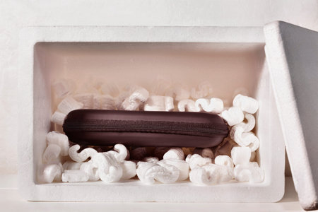 Black gift box in polystyrene box with packing peanuts, celebration event,
