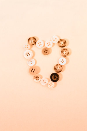 Buttons forming heart shape on peach colored background, passion and love, Valentine's dayの写真素材