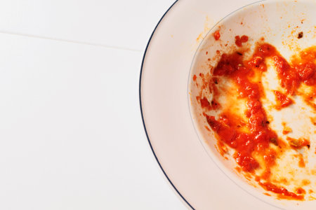 White dirty plate with red tomato sauce leftover, just ate