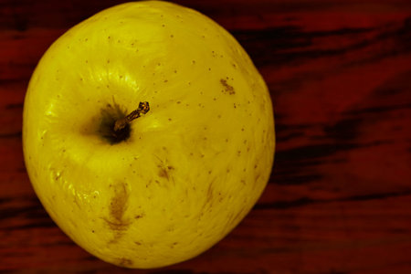 Whole yellow apple on wooden background ready to eat