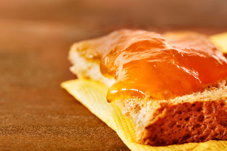 Orange fruit jam on slice of bread, ready for breakfast