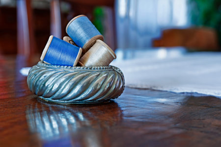 Spools of blue and yellow threads in bowl on wooden tableの写真素材