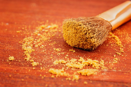Make up brush with yellow powder on brown wooden backgroundの写真素材