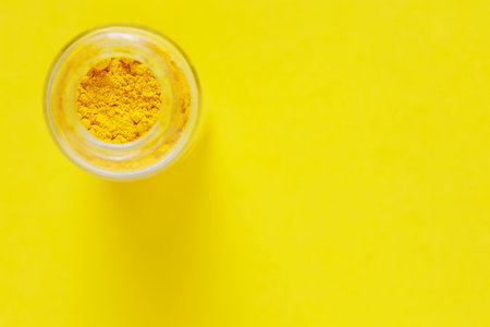 A vibrant yellow powder paint pigment in jar for creative projectsの写真素材