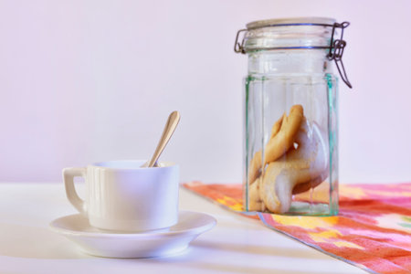 Cosy morning with with biscuits and cup of coffee on white table with colored cloth , peaceful day