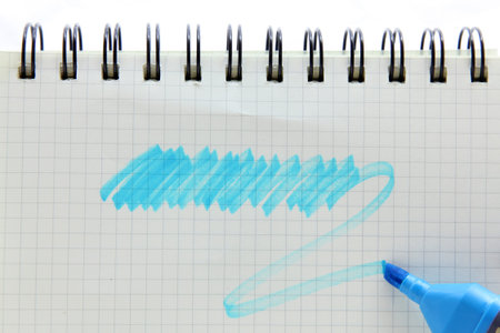 marker pen with scribbles on a blank vintage graph paper spiral binding note book, your text can be...