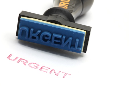 closeup of urgent letter on rubber stamp isolated on white backgroundの写真素材