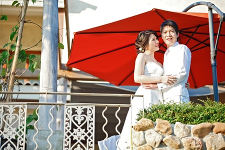 portrait of romantic bride and groom with red umbrellaの写真素材