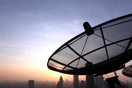 black antenna communication satellite dish over sunset sky in cityの写真素材