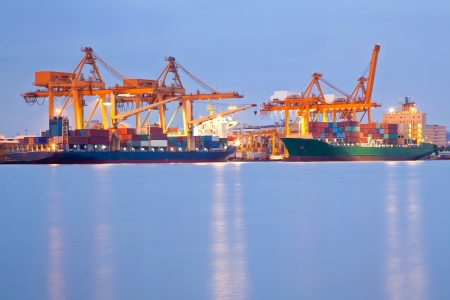 Big Container Cargo freight ship with working crane in shipyard at dusk for Logistic Import Export backgroundのeditorial素材
