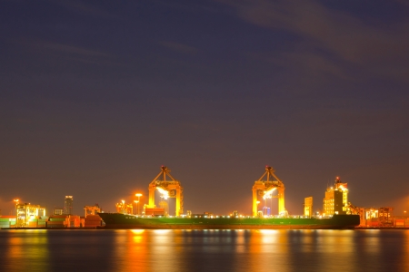 Container Cargo freight ship with working crane bridge in shipyard at dusk for Logistic Import Export backgroundの写真素材