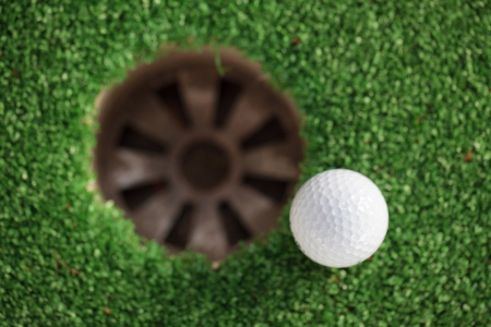 golf ball on lip of cup (Selective focus at golf ball)の写真素材