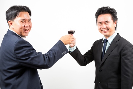 Two happy businessmen cheering up with flutes of wineの写真素材